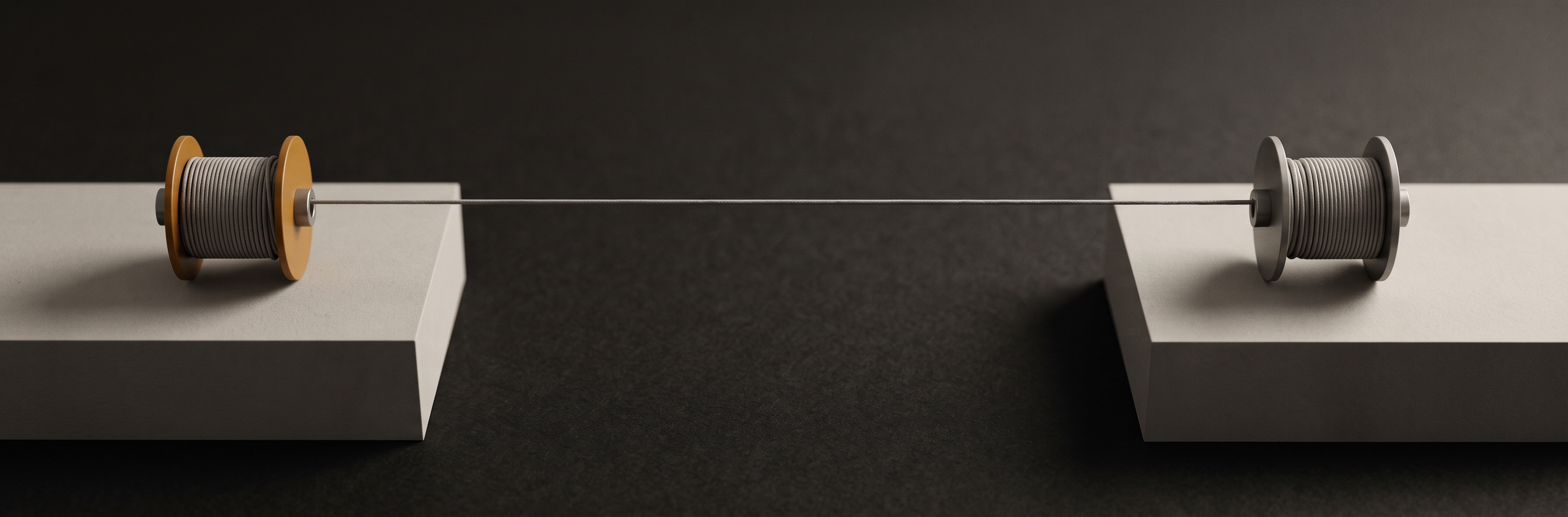 A taut cord running between two separate plinths, wound around a matching spool on each one.
